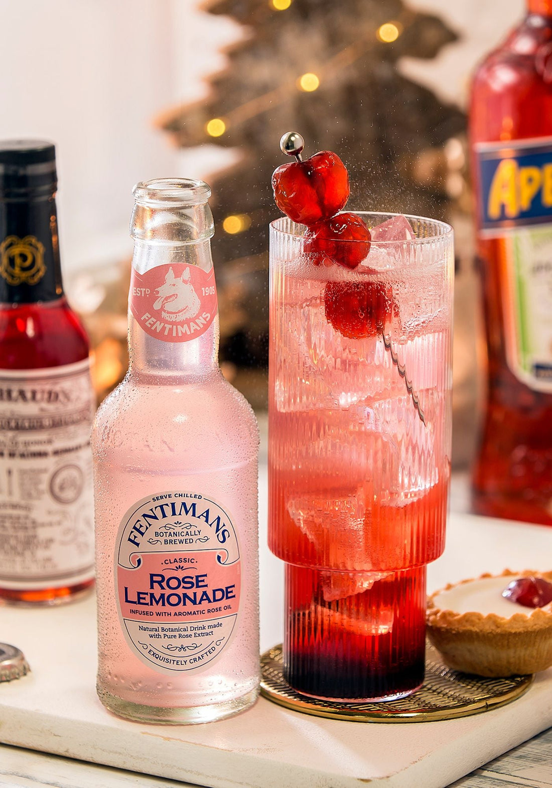 A bottle of Fentimans Rose Lemonade with a highball serve garnished with three cherries